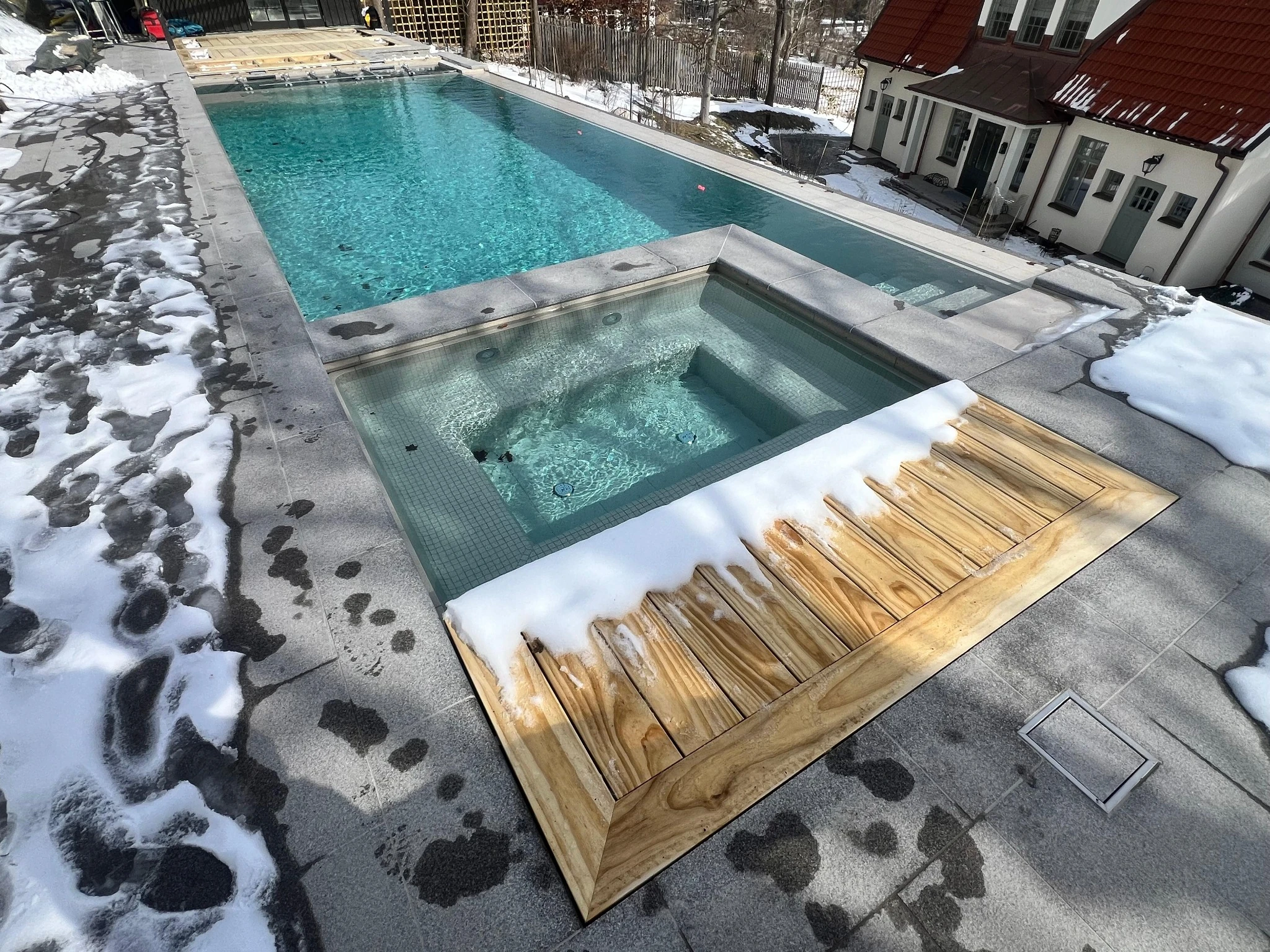 A Poolworks swimming pool and spa with clear turquoise water and stone surrounds