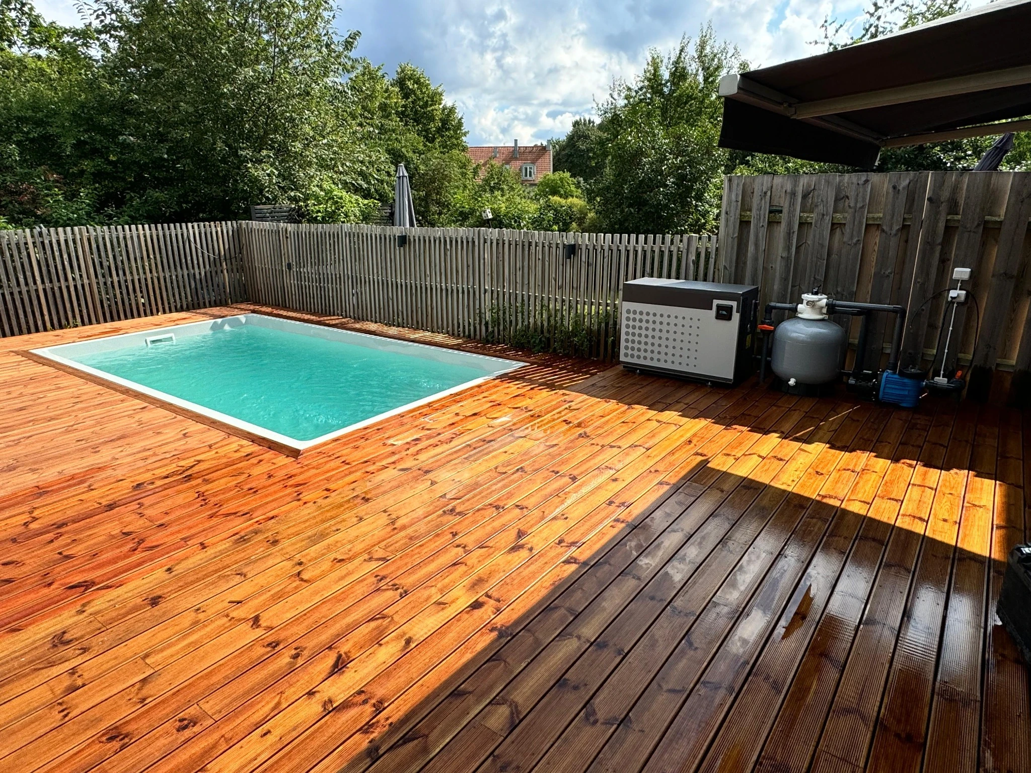 A Poolworks swimming pool in a sunny timber deck with its pump, filter and heat pump